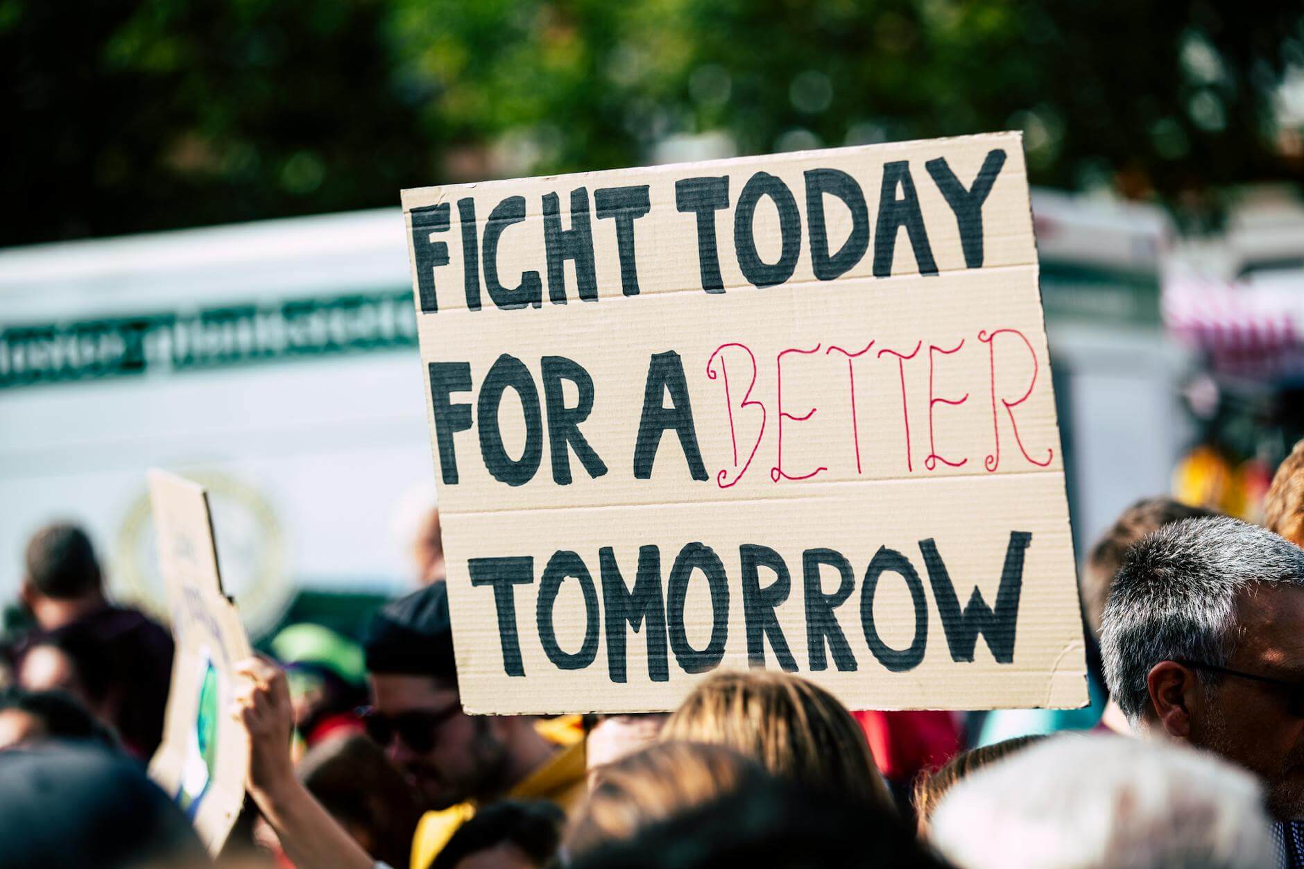 Fight Today for a Better Tomorrow cardboard sign held above a crowd at a protest
