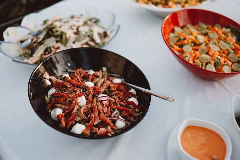 An array of gourmet salads with fresh ingredients served in bowls on a table outdoors.